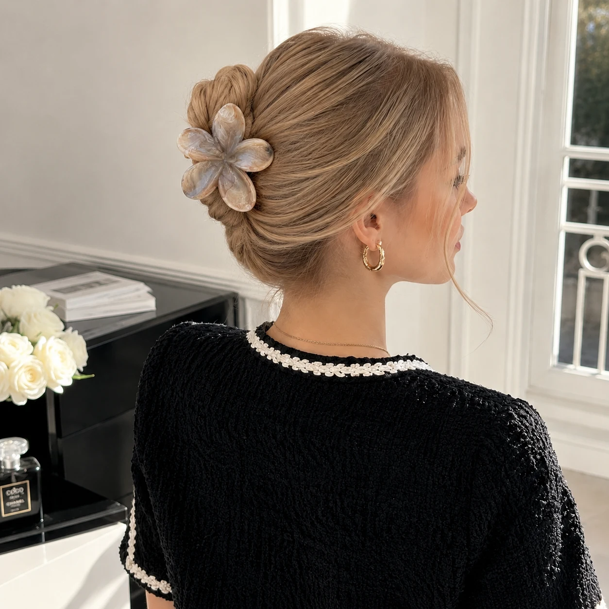 A neutral flower clip adding a delicate finishing touch to a chic black outfit