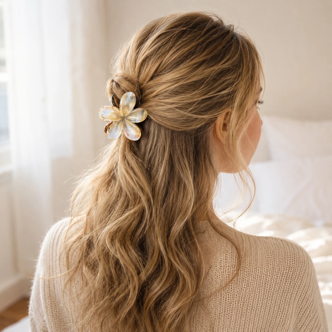 A soft cream and honey-toned flower clip in a loose half-up hairstyle